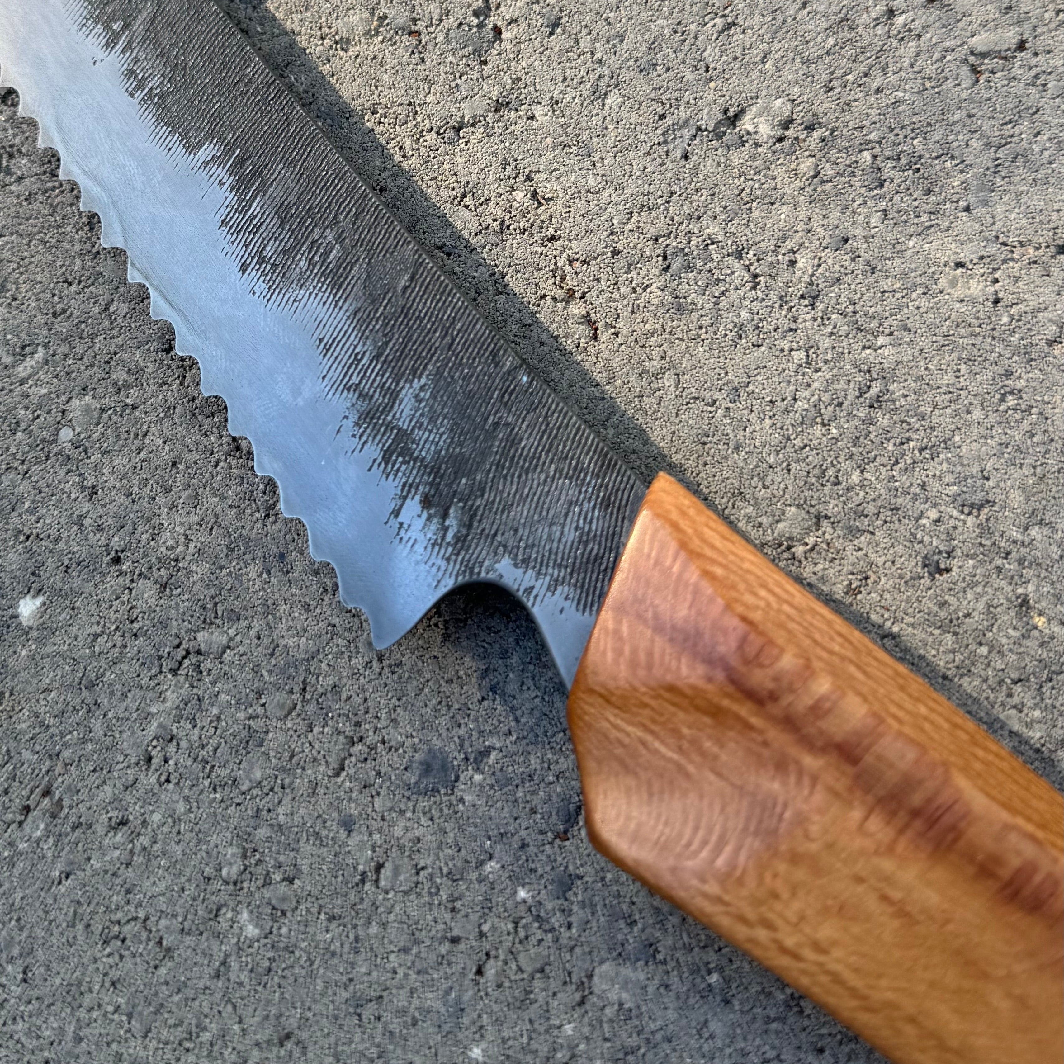 Serrated knife with wooden handle on a concrete surface